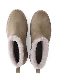 Bottines en suède marron avec des doublures douces et duveteuses. Bout arrondi et semelle en caoutchouc avec une texture antidérapante. Anse arrière pour un enfilage facile.