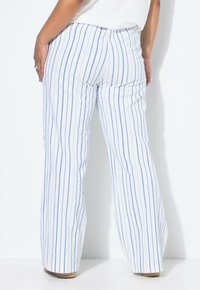 Weiße weit geschnittene Hose mit blauen vertikalen Streifen, aus strukturiertem Stoff und mit elastischem Bund. Sichtbare Nahtdetails an den Seiten.