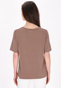 Brun kortærmet T-shirt med rund halsudskæring, glat tekstur og en afslappet pasform, vist fra ryggen mod en hvid baggrund.