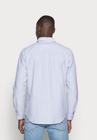 Ljusblå och vit randig långärmad skjorta med knapp-ner krage, axelsköld och manschetter med knappdetaljer.