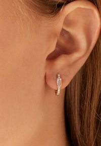 Zilveren hoepeloorbel met een rechthoekige edelsteen en kleine accentstenen langs de band, met een slank, modern ontwerp en een gepolijste afwerking.