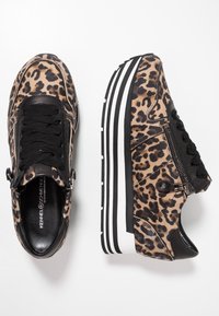 Trampki w panterkę mają teksturowaną cholewkę, czarne sznurówki oraz boczny zamek. Podeszwa platformowa ma kontrastowe czarno-białe paski.