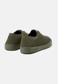 Tênis de malha verde com perfil baixo, sola de borracha e biqueira redonda. Apresenta um cabedal texturizado e sistema de atacadores. Branding discreto na lateral.