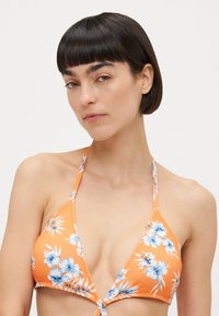 Top de biquíni em triângulo laranja com padrão floral azul, com alças finas, frente ajustável com laço e textura suave.