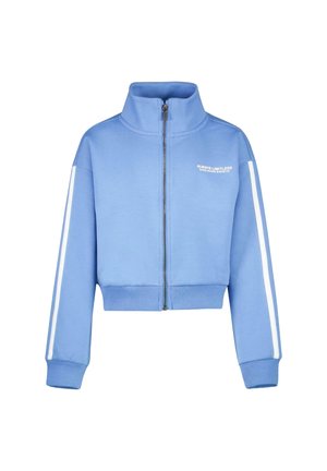 Lichtblauwe cropped hoodie met een hoge kraag, volledige rits en witte zijstrepen. Beschikt over zachte stof en geborduurde tekst op de borst.