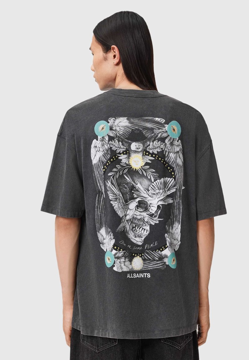 Tricou negru, de mari dimensiuni, cu un design grafic detaliat al unei schelete și păsări pe spate, cu accente colorate și text.