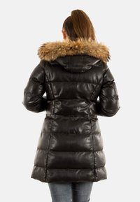 Abrigo acolchado negro de cuero con capucha de piel sintética, presenta un diseño acolchado, cintura ajustada y mangas largas. Textura suave con un acabado brillante.