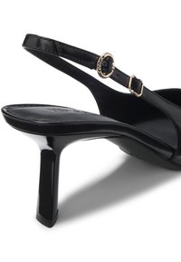 Black patent leather high-heeled sandal with a sleek pointed toe and adjustable ankle strap featuring a gold buckle detail.