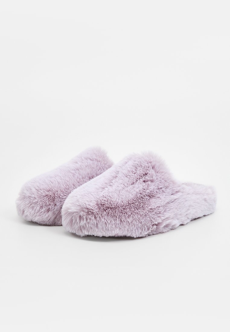 Lila Hausschuhe mit einer weichen, plüschigen Textur, offenem Design hinten und abgerundeter Form. Sie verfügen über eine flauschige Außenseite und ein gepolstertes Innere.