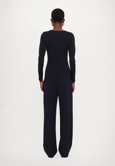 Navy long-sleeve top and wide-leg trousers; the top has a smooth texture and a classic neckline, paired with tailored flowing fabric pants.