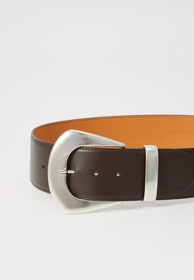 Bruine leren riem met een brede, zilveren metalen gesp met een gebogen vorm. De binnenkant heeft een contrasterende oranje voering. Gladde textuur.