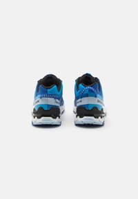 Baskets de sport bleues avec accents noirs, tige en mesh, semelle rembourrée et détails blancs et bleus contrastants. La vue arrière met en valeur un design texturé.