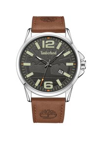 Timberland pulkstenis ar sudraba metāla korpusu, brūnu ādas siksnu, pelēku strukturētu ciparnīcu, lieliem gaismu atstarotājiem un datuma rādījumu.