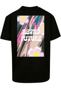 Melna T-kreka ar krāsainu grafiku uz muguras, kurā ir teksta "RETRO FUTURE", ko ieskauj rozā un dzeltenas ziedu uz viļņota fona.