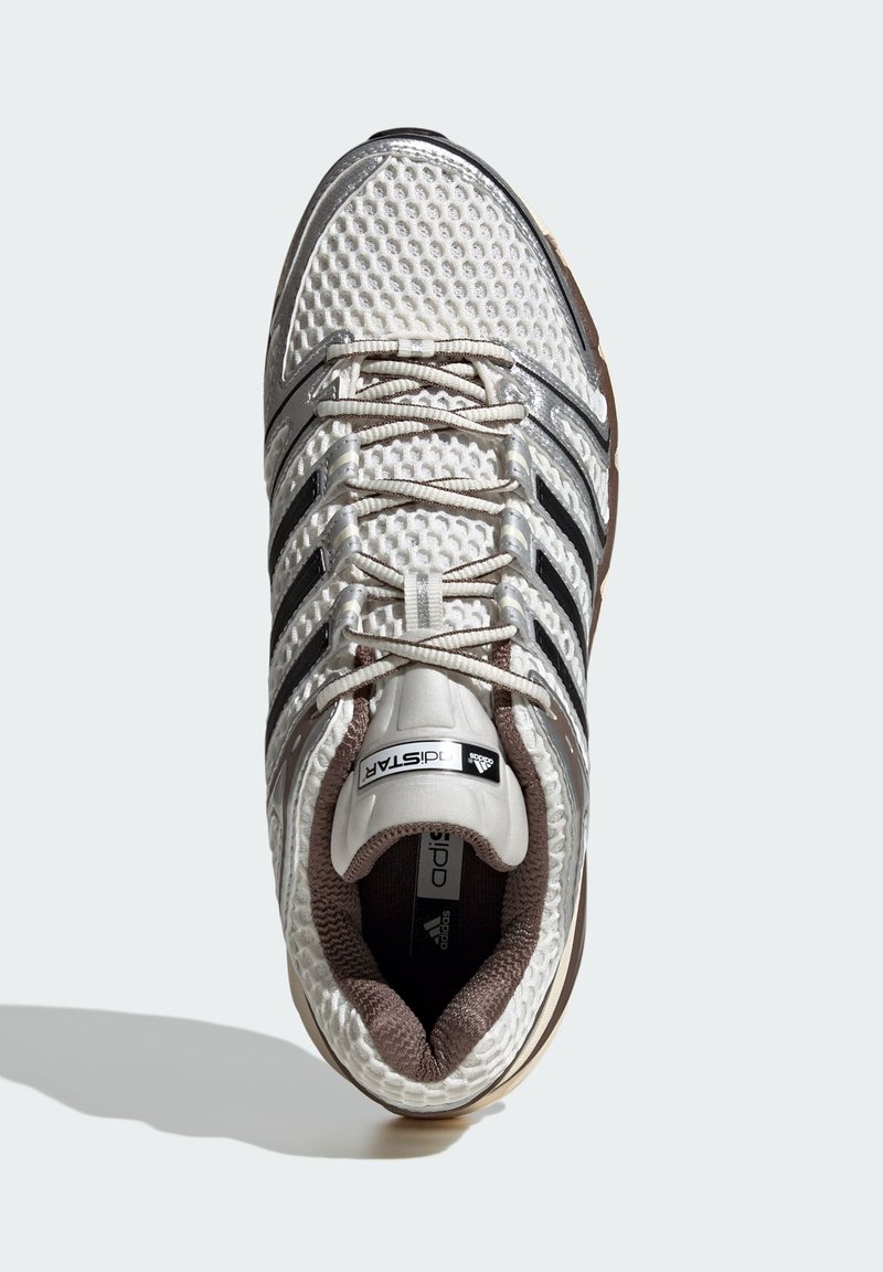 Weißer Sportschuh mit Obermaterial aus Mesh, silbernen Akzenten, schwarzen Streifen und strukturiertem Sohlenprofil. Verfügt über Schnürsenkel und einen gepolsterten Schaft.