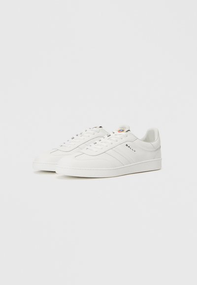 Adidașii albi din piele au un finisaj neted, vârf rotund, talpă plată din cauciuc, cusături contrastante și un mic logo pe lateral.