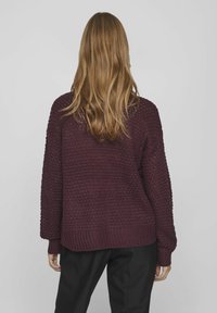 Burgundy stickad tröja med en texturerad mönster, sänkta axlar och ribbade manschetter, med en lös passform.