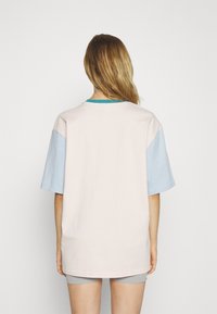 Överdimensionerad t-shirt med en rosa kropp och ljusblå ärmar, med en turkos halsringning. Tillverkad av mjukt bomullsmaterial.