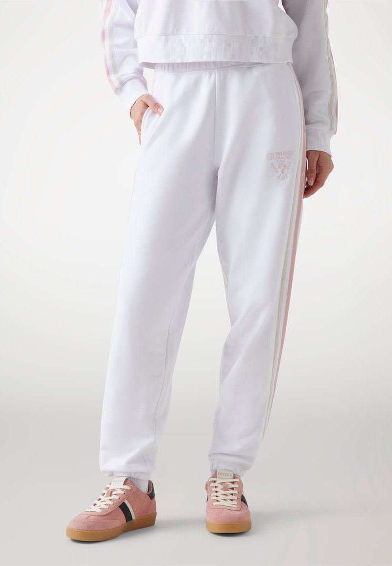 Witte sweatpants met zijstrepen in roze en crèmekleur, een elastische tailleband en zakken. Gecombineerd met roze sneakers met donkere accenten.