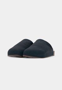 Tmavomodré slip-on topánky z mäkkého materiálu, s okrúhlou špičkou, minimalistickým dizajnom a štruktúrovanou podrážkou pre lepšiu trakciu.