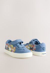 Kék gyerekcipők a Paw Patrol karaktereivel az oldalán, fűzőkkel és tépőzáras pánttal, fehér talppal.