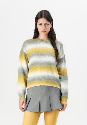 Knit sweater with yellow, gray, and white horizontal stripes, crew neckline, and dropped shoulders, paired with a gray pleated skirt and yellow tights.