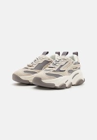 Chunky sneakers with a beige suede upper, contrasting mesh panels, and gray accents. Thick rubber sole designed for comfort and traction.