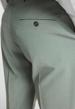 Pantaloni su misura verde chiaro con un design elegante, tessuto testurizzato e una tasca posteriore con dettagli di bottone nero.