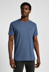 Blauwe korte- mouw t-shirt van textuurstof, met een borstzak en een klein merklabel. Ronde hals, normale pasvorm.