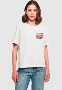 T-shirt en coton blanc avec un graphisme "ITALIAN FLAVOUR" rouge et vert, orné d'accents à carreaux sur le côté gauche de la poitrine. Manches courtes, coupe décontractée.