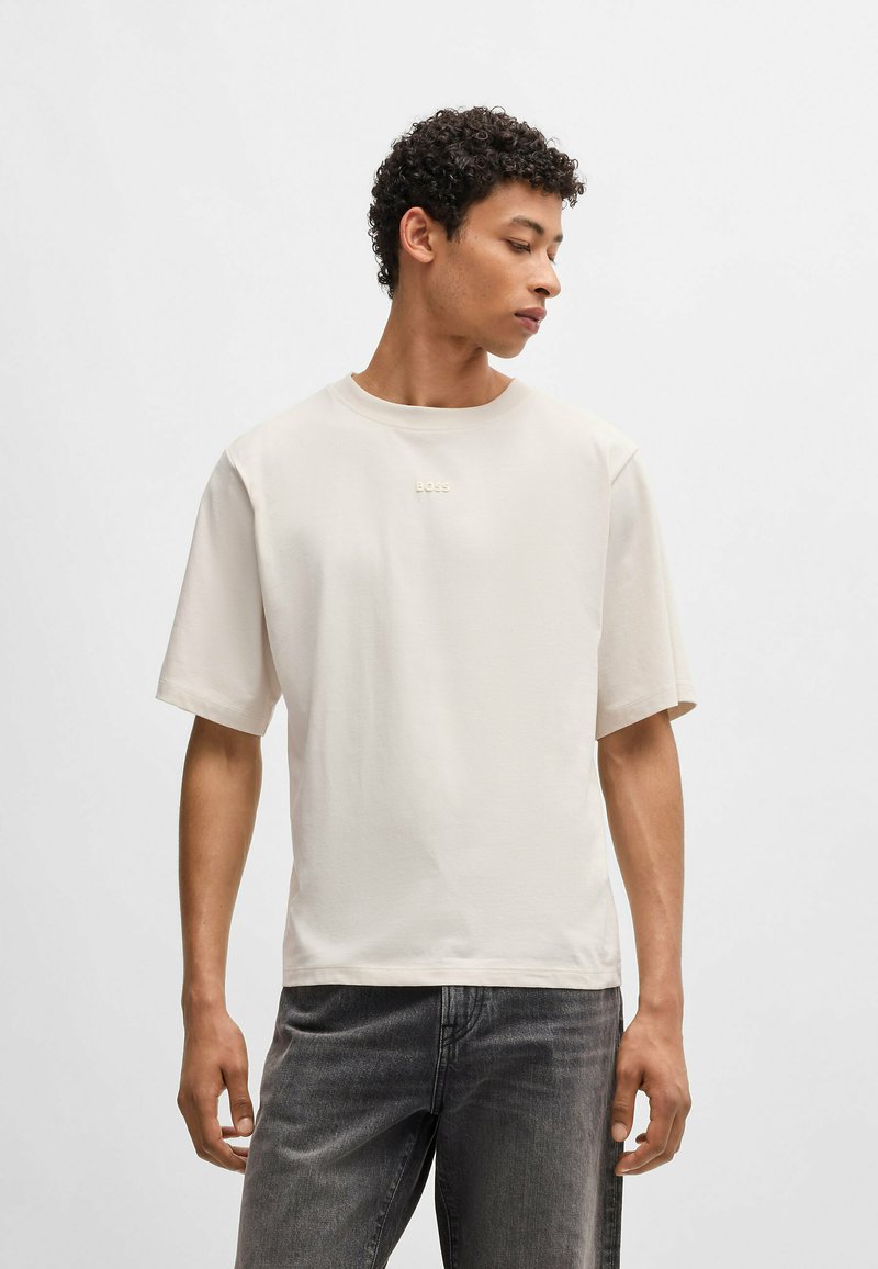 Lichtbeige T-shirt met korte mouwen, gemaakt van zachte katoen, met een ronde hals en een subtiel reliëf 'BOSS' logo op de borst.