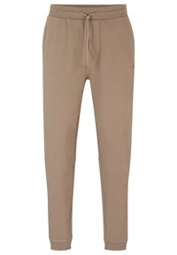 Beige jogger kalhoty vyrobené z měkké tkaniny, s elastickým pasem na šňůrku, bočními kapsami a úzkými manžetami na kotnících.