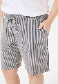 Shorts rayés navy et crème, avec une taille élastique et un cordon de serrage, des poches latérales et une coupe décontractée. Matière en mélange de coton.