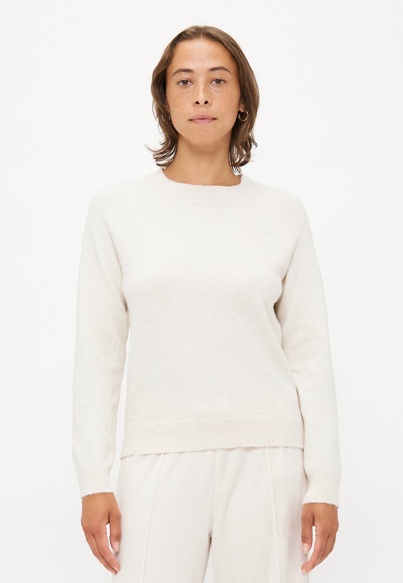 Suéter de color crema claro hecho de una tela suave. Presenta un escote redondo, mangas largas, puños acanalados y un dobladillo ligeramente cropped. Diseño minimalista.