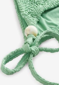 Mintgroene bikini top van structuurstof, met ingewikkelde smockdetails en een gestrikte sluiting met een glanzend witte kraalaccent.