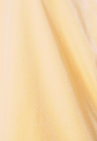 Tissu doux et lisse de couleur jaune clair avec des plis subtils créant des ombres et des reflets délicats.