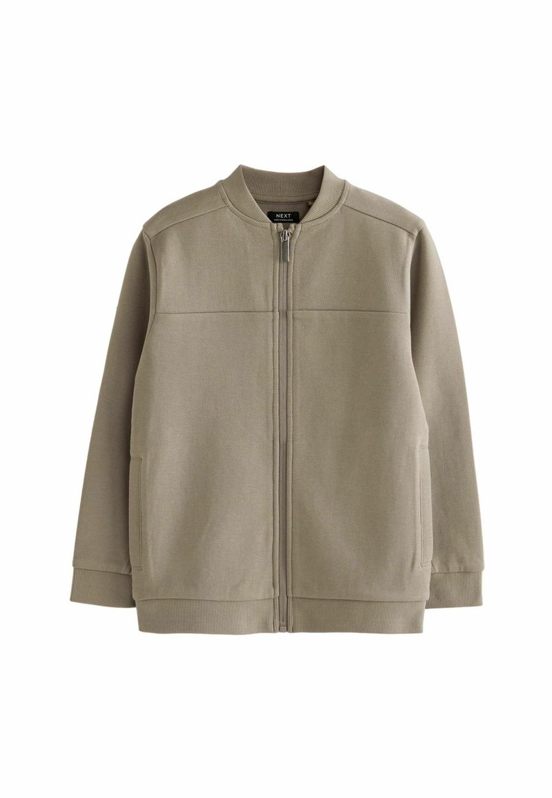 Veste zippée kaki en tissu texturé, avec un col rond, deux poches latérales et des poignets côtelés. Design simple et minimaliste.