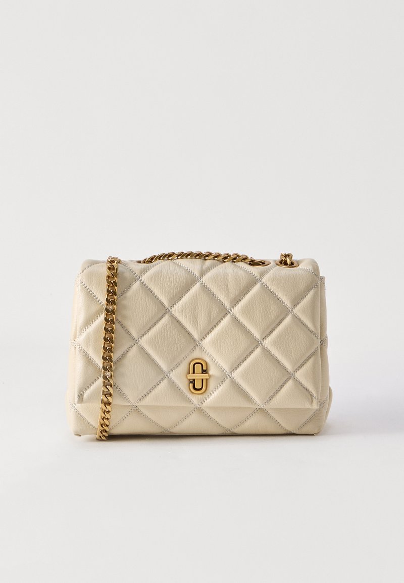 Μικρή μπεζ τσάντα χειρός με καπιτονέ ύφασμα, χρυσή αλυσίδα λουρί και χρυσό κούμπωμα, εμφανιζόμενη σε απλό λευκό φόντο.