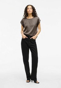 Brun satengtopp med korte ermer og rund hals, kombinert med høytlivs svarte jeans med rette ben og svarte heeled sandaler.