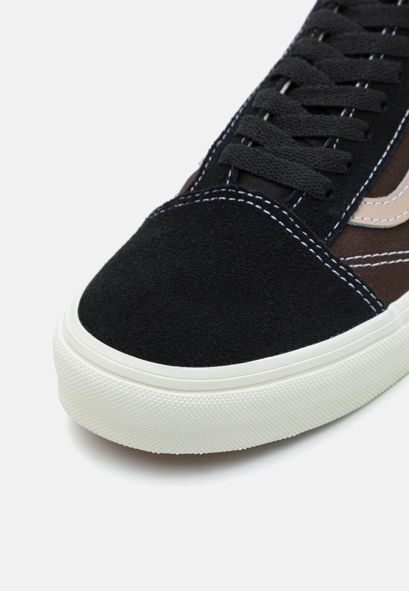 Schwarze Wildleder-Skate-Schuhe mit runder Zehenpartie, weißer Gummisohle und kontrastierenden braunen Akzenten, versehen mit schwarzen Schnürsenkeln und genähten Details.