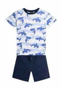 T-shirt aus Baumwolle mit Haifischmuster und blauen sowie weißen Wellen, kombiniert mit dunkelblauen Shorts mit elastischem Bund.