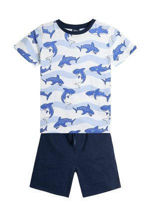 T-shirt aus Baumwolle mit Haifischmuster und blauen sowie weißen Wellen, kombiniert mit dunkelblauen Shorts mit elastischem Bund.