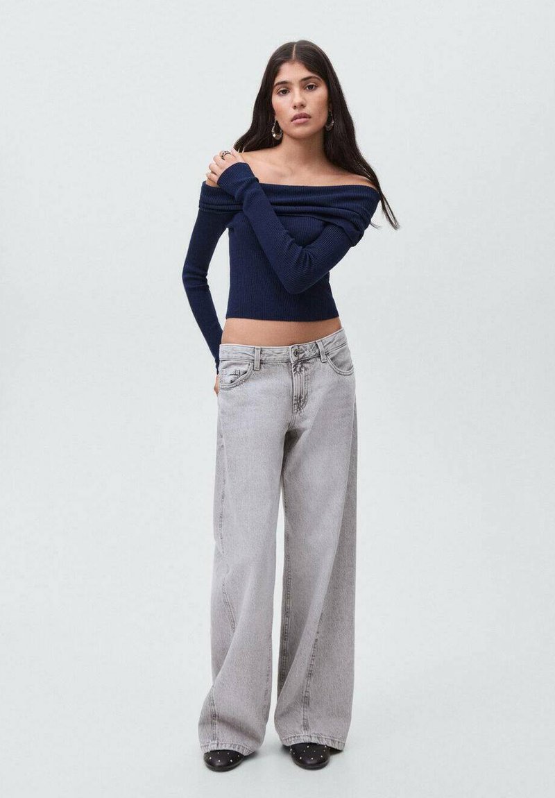 Námořnický top bez ramínek s žebrovaným vzorem spárovaný s vysokým pasem světlými šedými kalhotami s širokými nohavicemi. Kalhoty mají klasický styl s pěti kapsami.