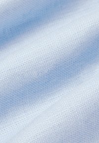 Jasnoniebieska tkanina o delikatnym, teksturowanym splocie, z miękkimi fałdami i gładką powierzchnią, wskazująca na lekkie materiały tekstylne.