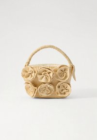 Sac à main en paille tissée de forme rectangulaire, orné de six accents floraux en tissu, de couleur beige clair, avec une anse recouverte de tissu.