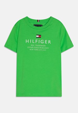 Helles grünes T-Shirt mit kurzen Ärmeln und Rundhalsausschnitt, weißer Schriftzug "HILFIGER", Markendetails und kleinem rot-weiß-blauem Logo über dem Schriftzug.