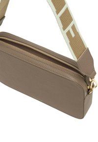 Taupefarbene rechteckige Leder-Umhängetasche mit goldenem Reißverschluss und breitem beigem Stoffriemen mit weißem Schriftzug.