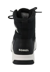 Černá zimní bota Sorel s vysokým polstrovaným límcem, bílou podrážkou, logovou nášivkou a texturovanými gumovými detaily. Má příchytky pro snadné nazouvání.