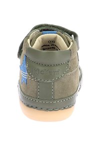 Zapato de cuero y ante verde con un acento de estrella azul, un collar acolchado y una suela de goma beige. Presenta una correa de velcro para el cierre.