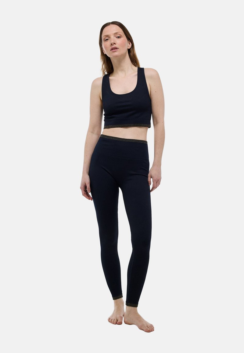 Haut court côtelé bleu marine avec des bretelles larges et un accent pailleté sur l'ourlet, associé à un legging taille haute assorti. Tissu doux et extensible.